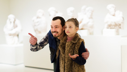 Father and daughter looking at classical statues