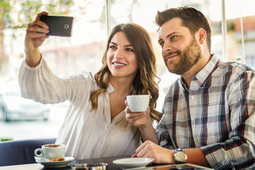 Selfie time at public. Couple at cafe making self portrait mobile phone.