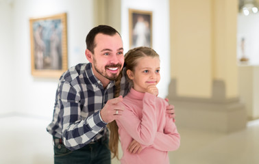 Father and small daughter exploring art paintings