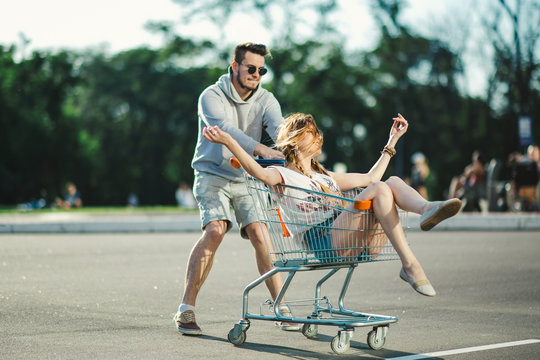 Happy love couple having fun 
with a supermarket trolley
