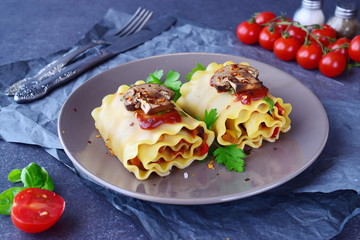 Pasta rolls with vegetables: paprika, onion, olives, mushrooms, tomato on a light brown plate on a grey abstract background. Vegetarian food. Dieting. Mediterranean lifestyle