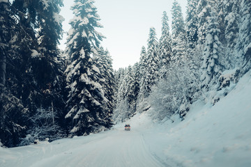 the car is riding on the snow road in the mountains