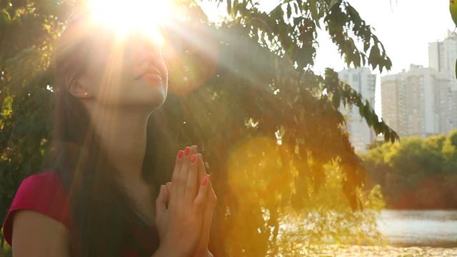 Beautiful young woman praying to God outdoor with sunshine
