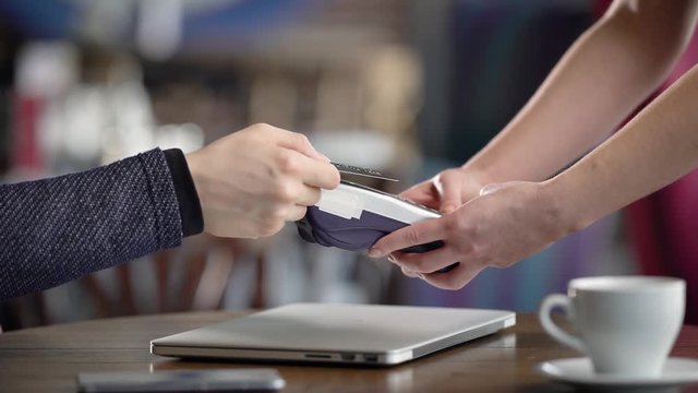 Using Credit Card Terminal in cafe. Close-up, male hands with a credit card. Payment without contact method.
