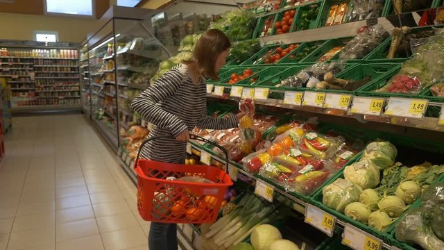 Woman buys vegetables in supermarket