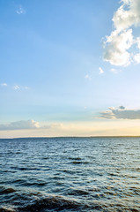 Beautiful sea, river, lake, reservoir. Natural panorama in the rays of the setting, the rising sun. A magnificent blue sky with neat clouds. 
