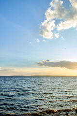 Beautiful sea, river, lake, reservoir. Natural panorama in the rays of the setting, the rising sun. A magnificent blue sky with neat clouds. 