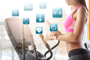 Young woman with fitness tracker training in gym