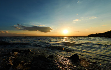 Beautiful sea, river, lake, reservoir. Natural panorama in the rays of the setting, the rising sun. A magnificent blue sky with neat clouds.