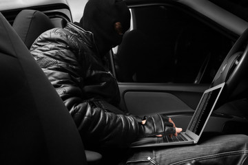 Thief hacking car security system with laptop