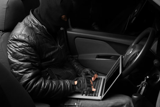 Thief hacking car security system with laptop