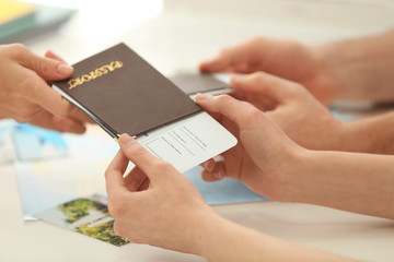 Adventure concept. Hands of young woman receiving passport with ticket at travel agency