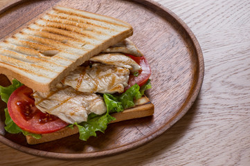 Sandwich with chicken on wooden plate, flat lay top view.