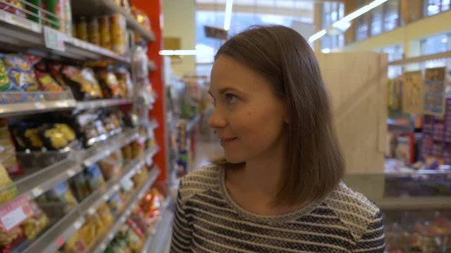 Woman walks along aisle in supermarket