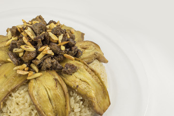 Arabic food, Rice with fried eggplant slices over it, adorned with cubs of meat almond and Pine grains, It's name in Syria : Makluba