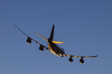 Airplane flying in the blue sky. Sun glare on the aireplane below