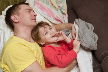 the father embraces the kid lying in a bed at home