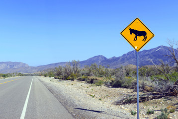 Donkey or burro crossing warning sign on road in the desert in the southwest, USA