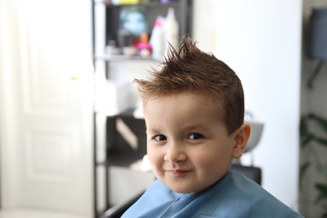 happy little kid with a modern hairstyle in the barbershop
