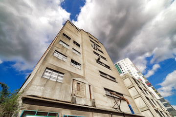 Derelict warehouse building by an old port against the backdrop of a cloudy and blue sky