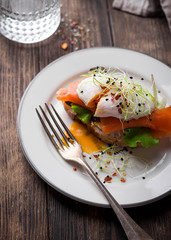 Delicious toast with salad, salted salmon and poached egg on rustic background;