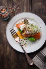 Delicious toast with salad, salted salmon and poached egg on rustic background;