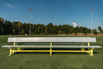 Empty aluminum bench team sports background on a green turf field