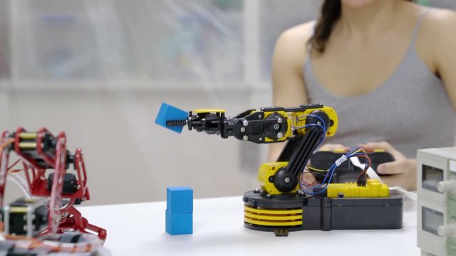 young female scientist adjusting the robot arm