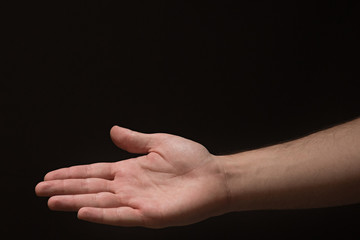 Right hand Extended male arm with open palm on a black background