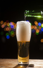 Beer is pouring into glass on bar lights background