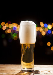 Glass of beer on bar lights background