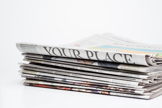 Close up of a stack of folded newspapers on white background
