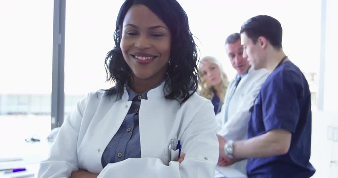 Confident female doctor in front of team looking at camera smiling multiracial team with black female doctor