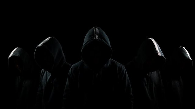 Five mysterious hooded men standing in the dark
