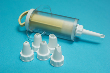 Cream injector (cooking bag) and set of cream piping nozzles on blue background.