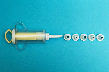 Cream injector (cooking bag) and a set of cream piping nozzles on a blue background, top view.