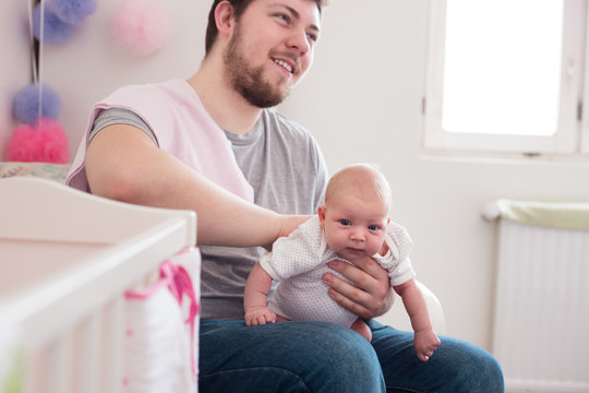 Young father burping his newborn daughter, holding her affectionately. Lifestyle shoot with natural light.