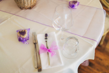 Obraz na płótnie Canvas Wedding table setting at a banquet. A plate and instruments tied with a purple ribbon.