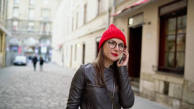 Woman with red lips talking on the smartphone and strolls along the medieval street