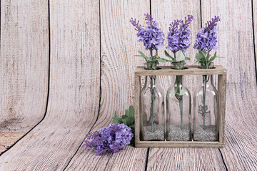 Flores de lavanda en botellas de cristal y soporte de madera.