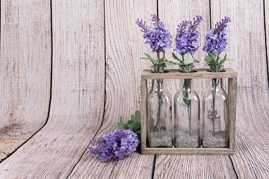 Flores de lavanda en botellas de cristal y soporte de madera.