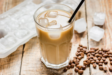 coffee break with cold iced latte and beans on wooden table background