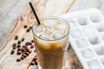 coffee ice cubes and beans with latte on wooden desk background