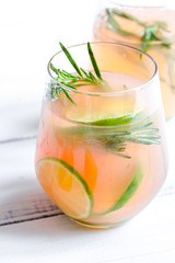 glass of fresh juice with lime and rosemary on white table background