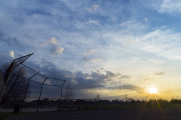 Silhouette of baseball diamond fence at dawn, beautiful sunrise sky with space for text
