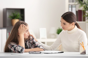 Young female psychologist working with teenager girl in office