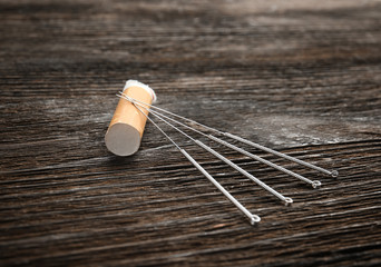 Cigarette butt with needles on wooden table