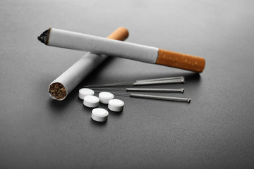 Cigarettes with needles and pills on table
