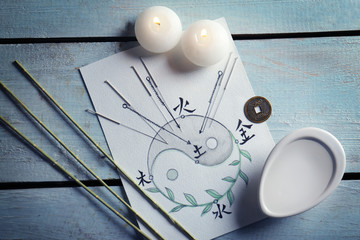 Acupuncture needles with candles and drawing on wooden background - obrazy, fototapety, plakaty