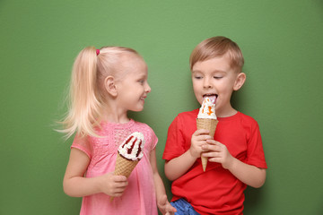 Cute little children eating ice cream on color background